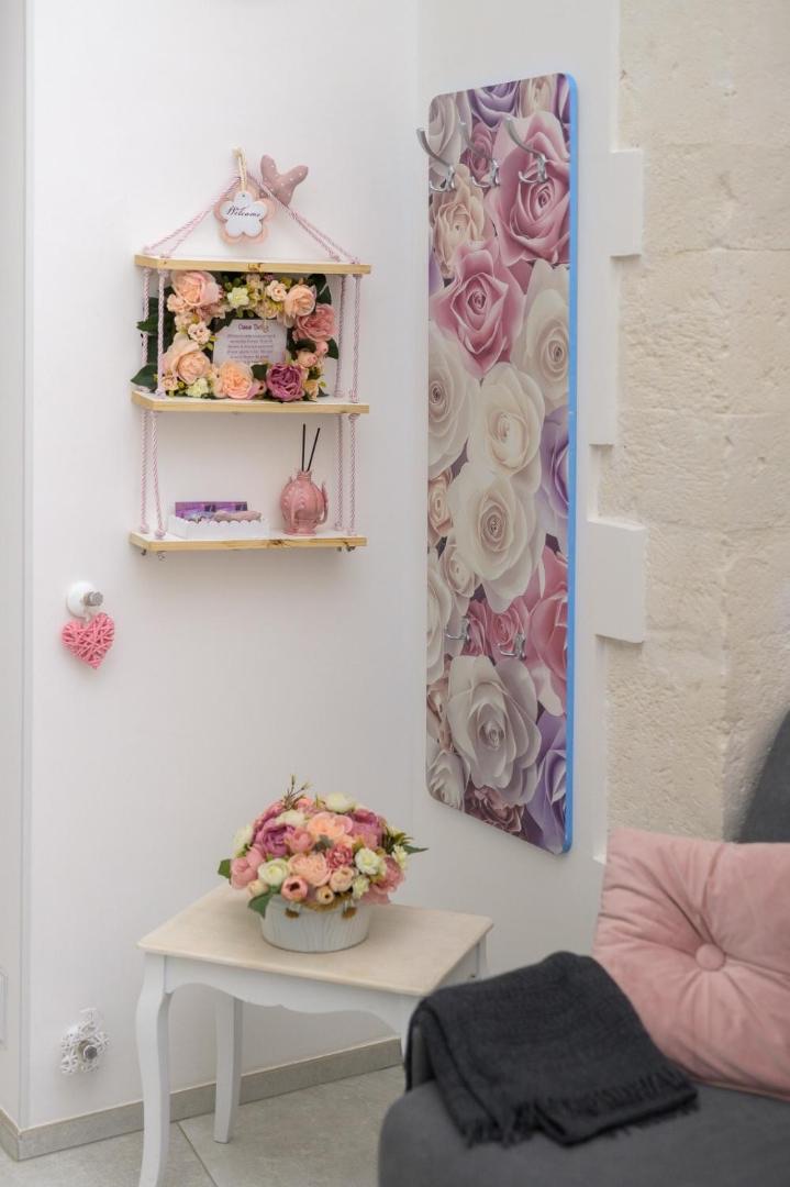 Mensola decorata con composizione di fiori e quadro floreale accanto al letto