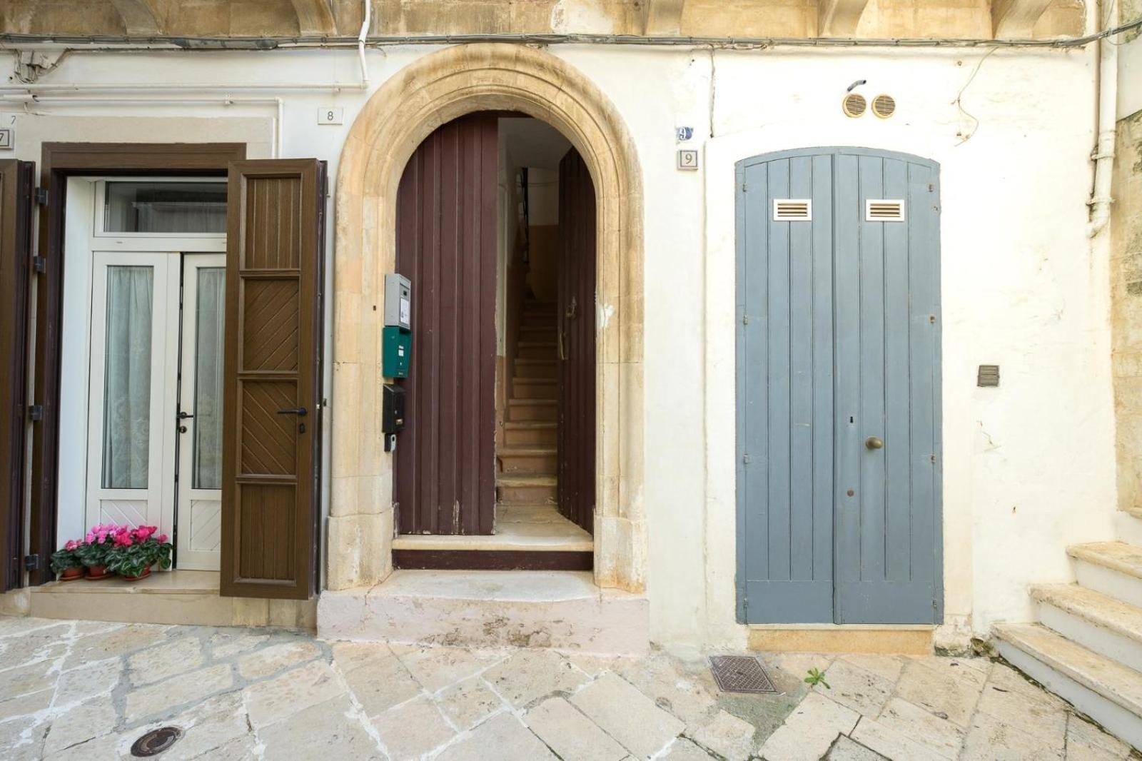 La facciata di Casa Deky: portale in pietra ad arco e porta d'ingresso su una via del centro storico di Martina Franca
