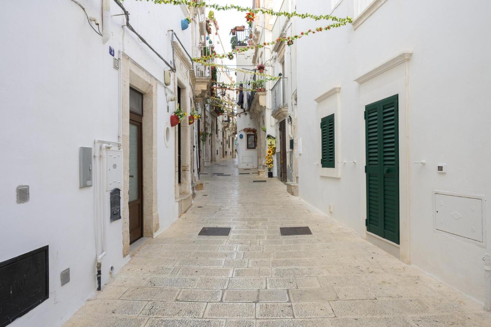Il vicolo imbiancato del centro storico di Martina Franca, con le persiane verdi, a pochi passi da Casa Deky