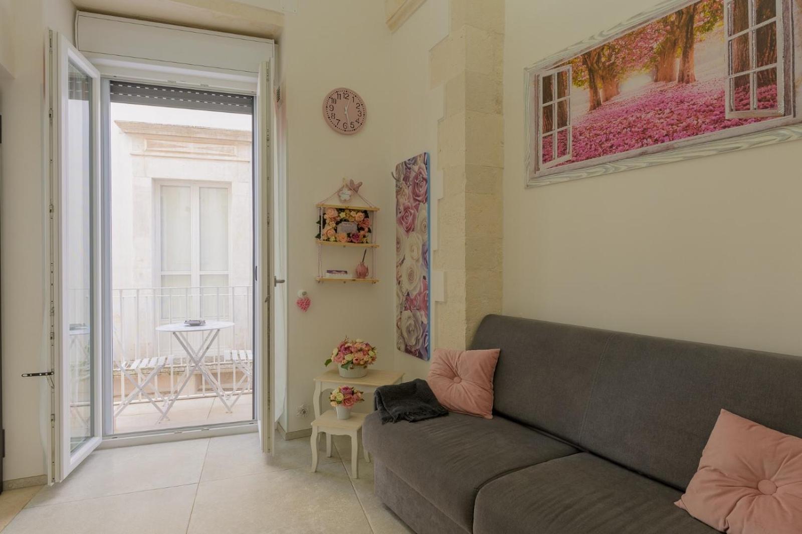 La zona giorno di Casa Deky con divano letto e porta-finestra che si apre sul balcone