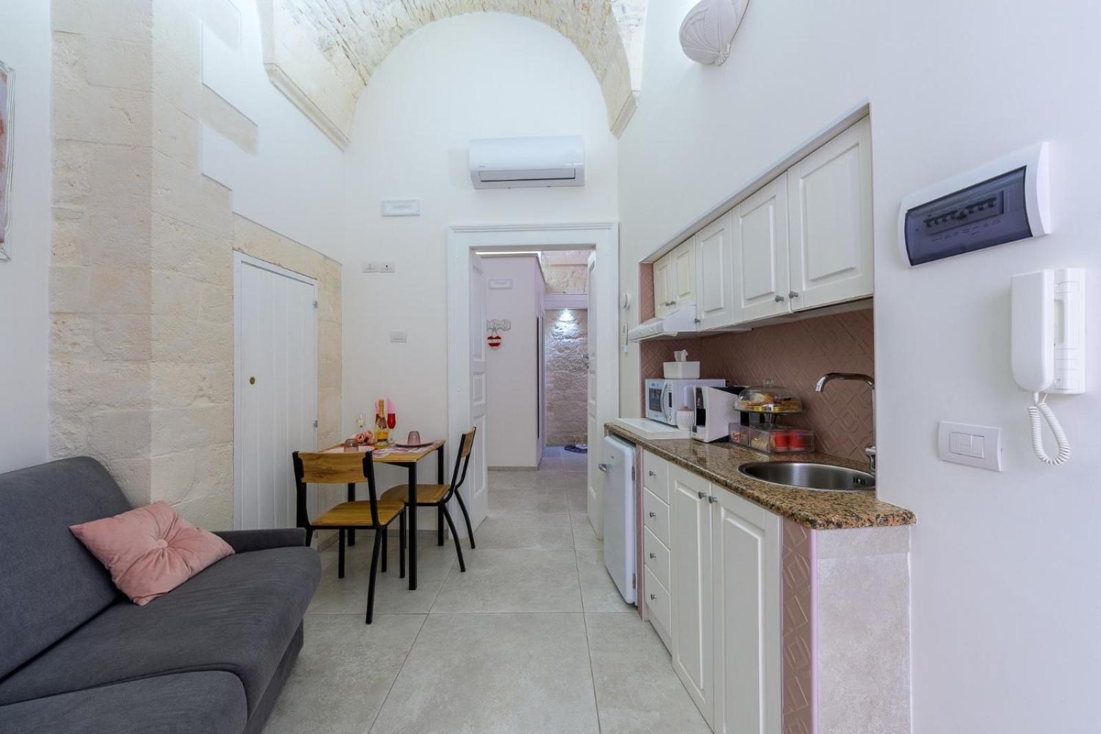 L'ambiente di Casa Deky per il lungo: divano, tavolo da pranzo e angolo cottura attrezzato sotto la volta a stella